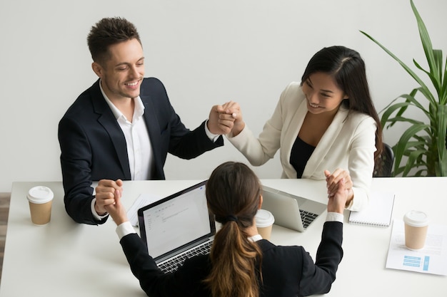 Equipo de negocios meditando juntos tomados de la mano