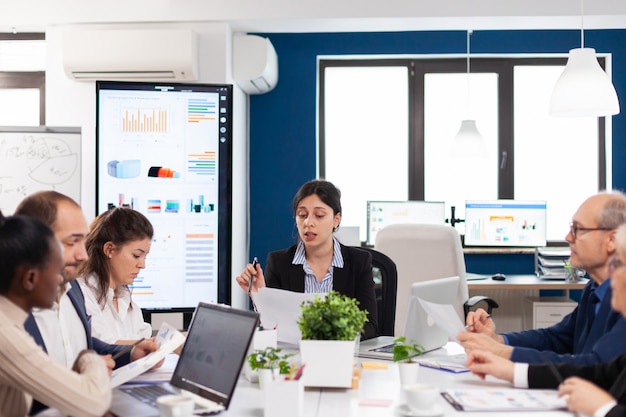 Equipo de negocios multiétnico sentado a la mesa en el centro de la oficina hablando