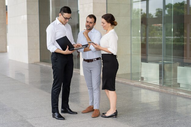 Equipo de negocios seguro leyendo y discutiendo papeles al aire libre