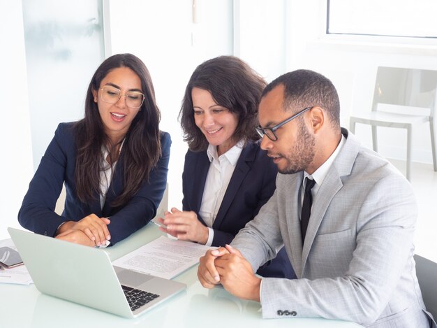 Equipo de negocios sonriente usando laptop