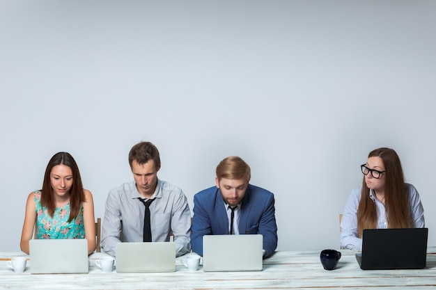 Equipo de negocios trabajando juntos en la oficina sobre fondo gris claro. todos trabajando en portátiles. imagen de copyspace