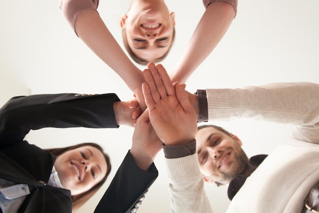 Un equipo de negocios unidos exitoso juntó las manos, vista desde abajo