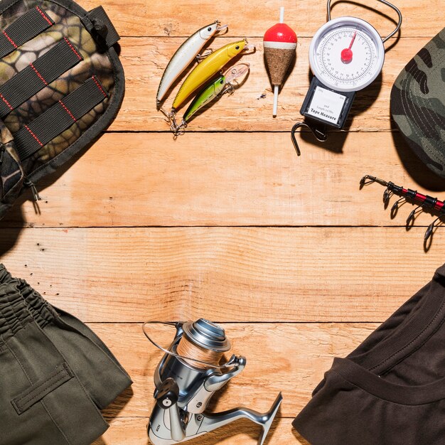 Equipo de pesca y ropa masculina sobre tabla de madera.