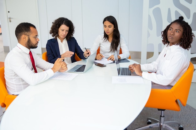 Equipo profesional de negocios con laptops y papeles.