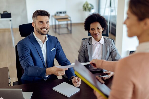 Equipo de recursos humanos feliz tomando CV de candidato potencial durante la entrevista de trabajo