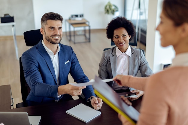 Equipo de recursos humanos feliz tomando CV de candidato potencial durante la entrevista de trabajo