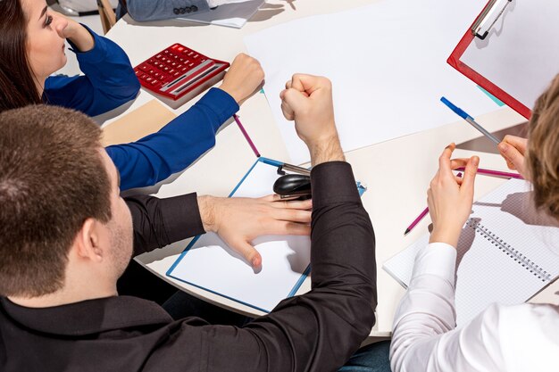 Equipo sentado detrás del escritorio, revisando informes, hablando. El concepto empresarial de colaboración, trabajo en equipo, reunión.