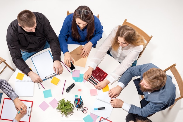 Equipo sentado detrás del escritorio, revisando informes, hablando. Vista superior. El concepto empresarial de colaboración, trabajo en equipo, reunión.