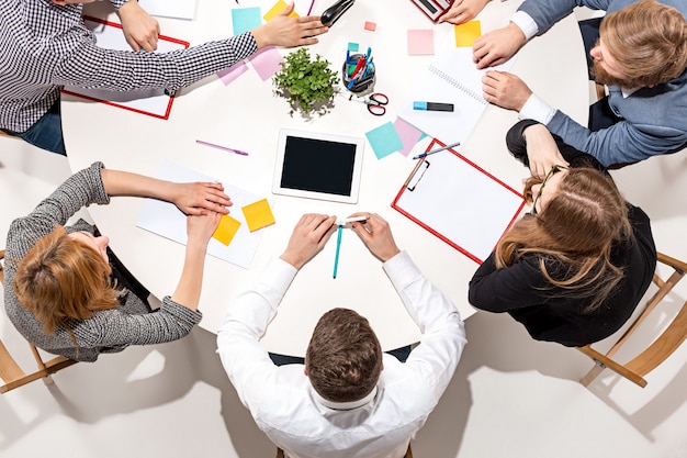 Equipo sentado detrás del escritorio, revisando informes, hablando. Vista superior.