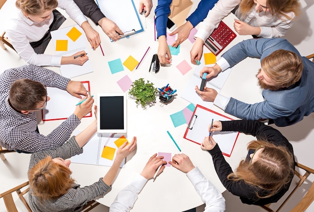 Equipo sentado detrás del escritorio, revisando informes, hablando. Vista superior.