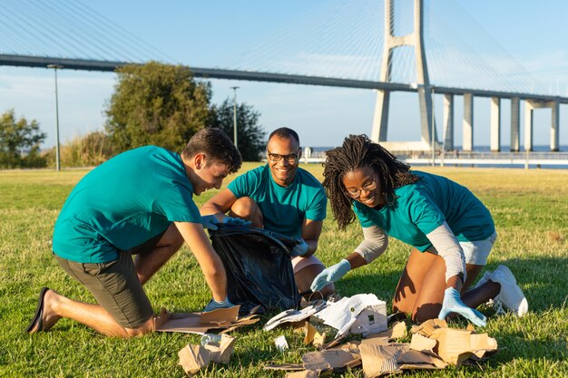 Equipo voluntario feliz que limpia área verde de la ciudad