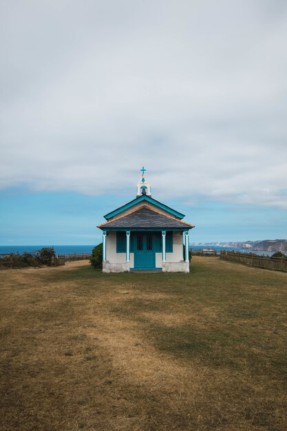 La Ermita de La Regalina rodeada por el mar bajo un cielo nublado en Asturias, España