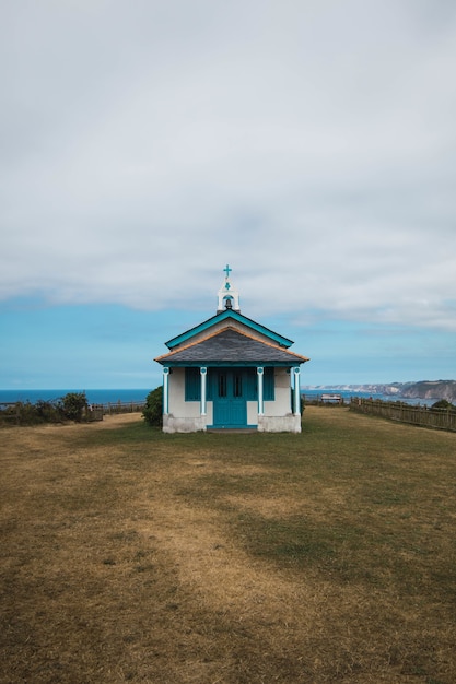 La Ermita de La Regalina rodeada por el mar bajo un cielo nublado en Asturias, España