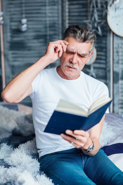 Es hora de enrojecer al anciano barbudo con su libro favorito, sentado en el sofá