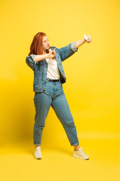 Es más fácil ser seguidor. Necesita ropa mínima para selfies. Retrato de mujer caucásica sobre fondo amarillo. Modelo de pelo rojo mujer hermosa. Concepto de emociones humanas, expresión facial, ventas, publicidad.