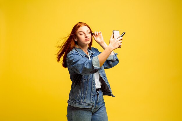 Es más fácil ser seguidor. No necesitas una selfie para maquillarte. Retrato de mujer caucásica sobre fondo amarillo. Modelo de pelo rojo mujer hermosa. Concepto de emociones humanas, expresión facial, ventas, publicidad.