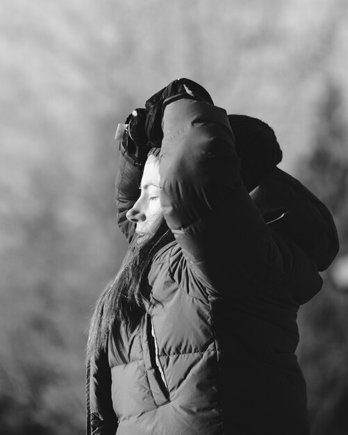 Escala de grises de una mujer con las manos en la cabeza bajo la luz del sol