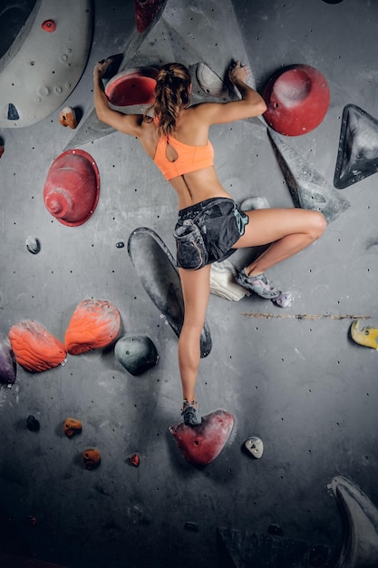 Escalada femenina deportiva en un muro de escalada interior.