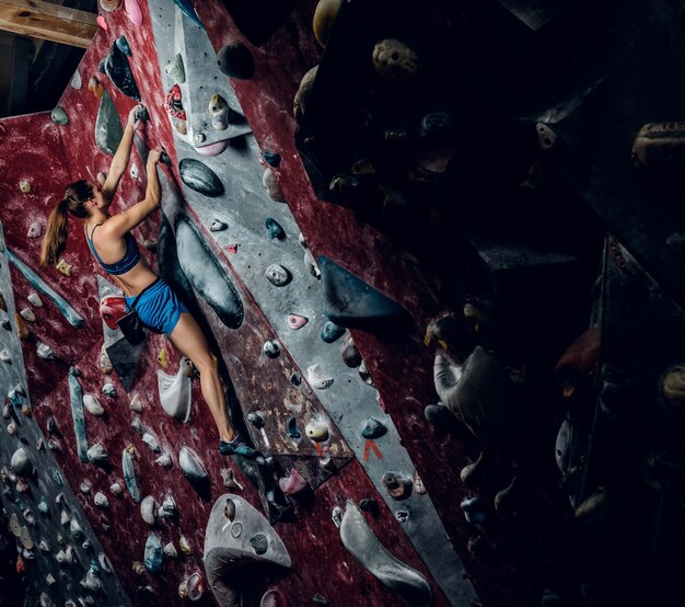 Escalador libre femenino boulder en interiores. Vista trasera.