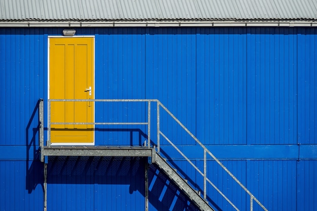 Escalera cerca de la pared azul de un garaje que conduce a la puerta amarilla
