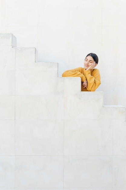 Escalera inclinada de mujer con los ojos cerrados.