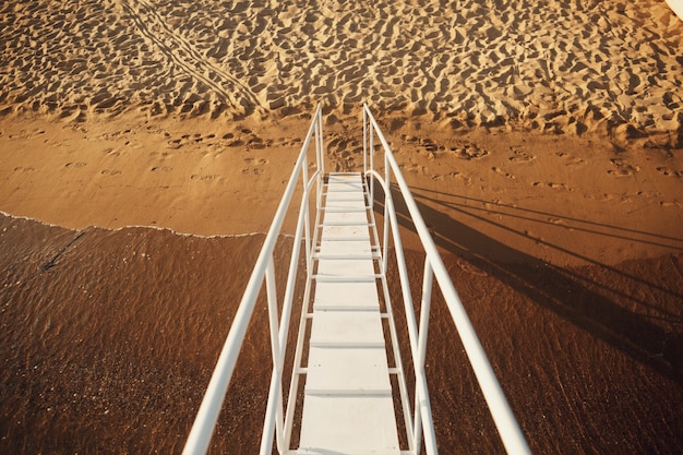 Escaleras blancas conducen a la playa desde el barco