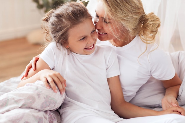 Escena familiar. Feliz madre e hija en una cama