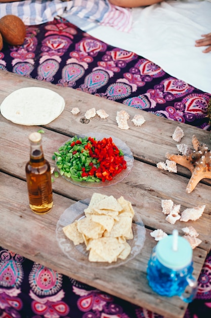 Escena de fiesta de playa con comida y bebida en tablón de madera