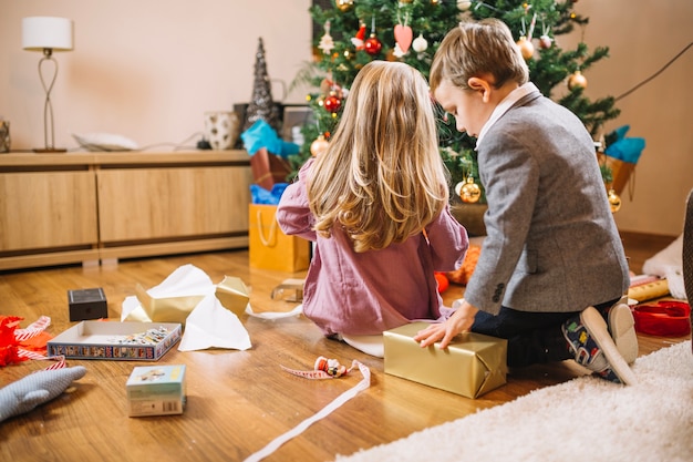 Escena de navidad con dos niños enfrente de árbol