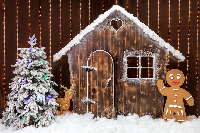 Una escena navideña con una cabaña cubierta de nieve, un hombre de jengibre y un árbol de navidad. decoración del bosque de cuento de hadas. | Foto Premium
