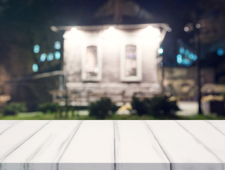 Foto gratuito escritorio blanco frente a la casa borrosa por la noche