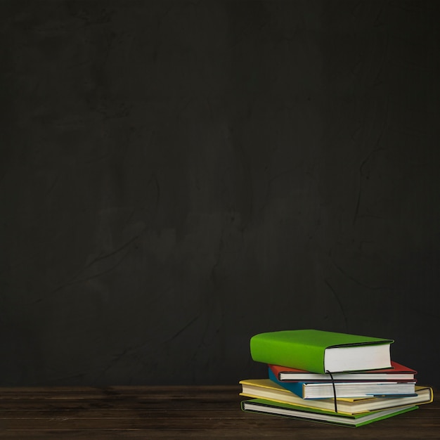 Escritorio con libros cerca de la pared negra