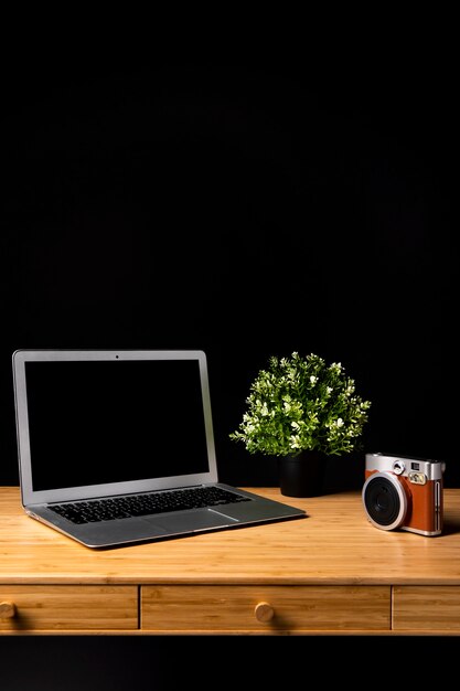 Escritorio de madera con laptop y cámara.