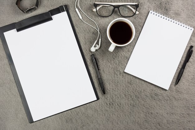 Escritorio de oficina gris con taza de café; auriculares y gafas