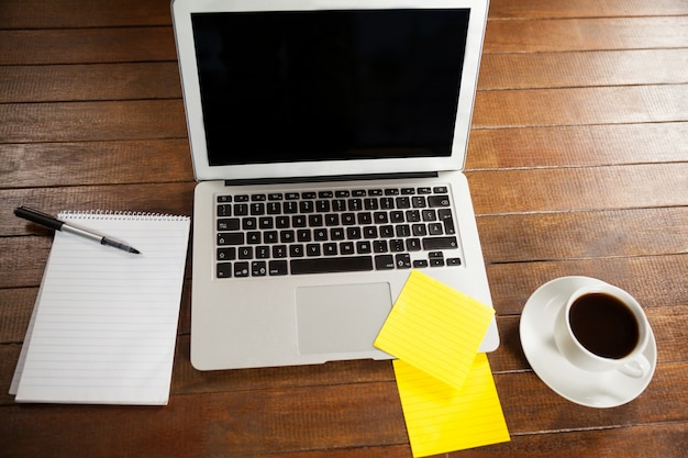 escritorio de oficina con el ordenador portátil, bloc de notas y una taza de café