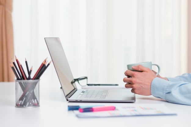 Escritorio de oficina con ordenador portátil y una taza de café