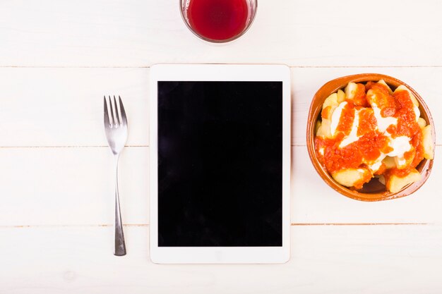 Escritorio con tableta y plato de comida