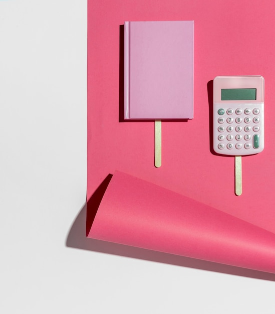 Escritorio de vista superior minimalista cuaderno rosa y calculadora