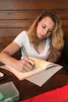 Foto gratuita escritura hermosa de la mujer joven en cuaderno