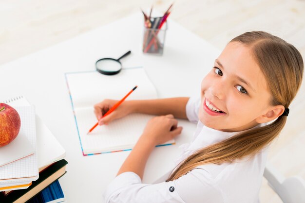 Escritura inteligente de la colegiala en el cuaderno