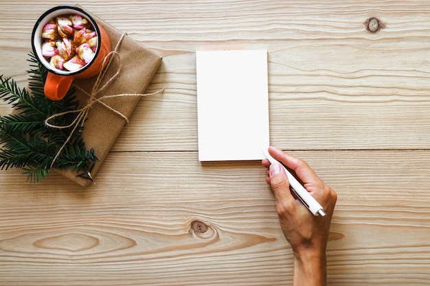 Escritura de la mano de la cosecha en cuaderno cerca del presente y bebida