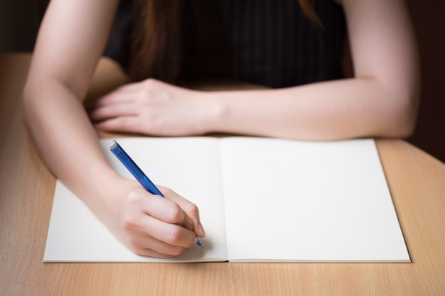 Foto gratuita escritura de la mano de la mujer en el libro en blanco