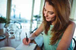 Foto gratuita escritura de la mujer en la libreta