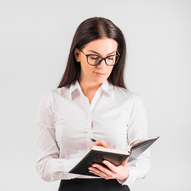 Foto gratuita escritura pensativa de la mujer de negocios en cuaderno con la pluma