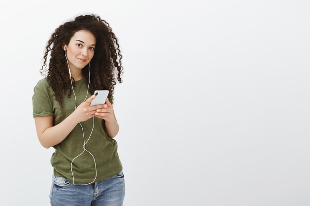 Escuchando nueva pista de cantante favorito. Retrato de mujer guapa despreocupada satisfecha con el pelo rizado