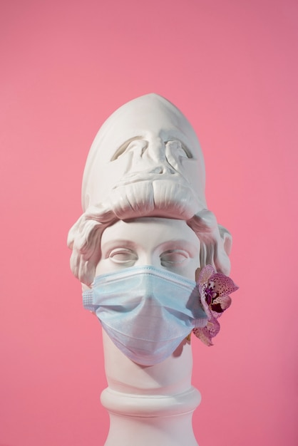 Escultura de mármol de figura histórica con máscara médica y orquídea.