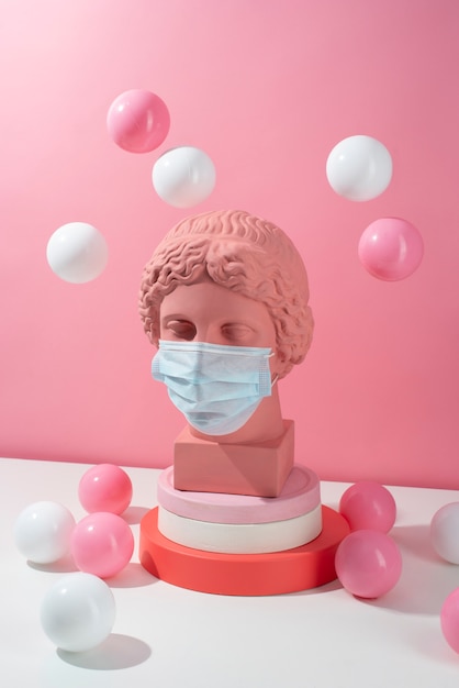 Escultura de mármol de figura histórica con máscara médica y pelotas.