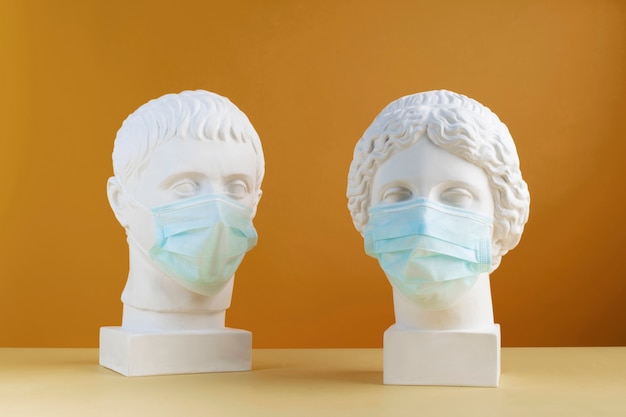 Esculturas de mármol de personajes históricos con máscaras médicas
