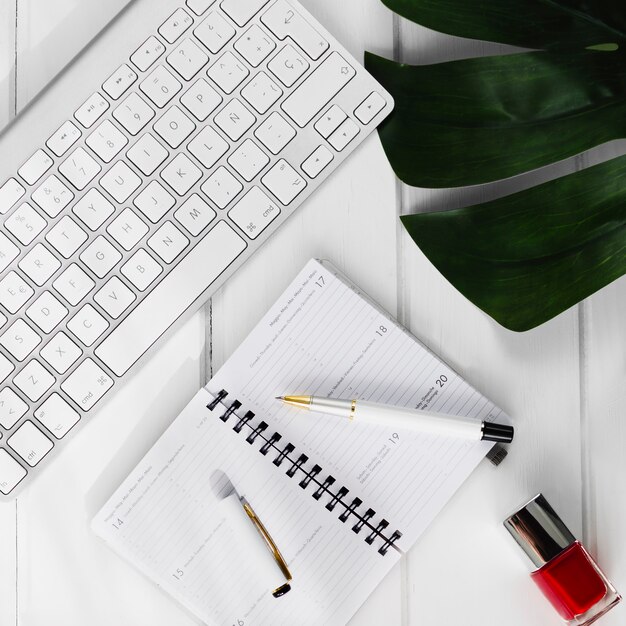 Esmalte de uñas y cuaderno cerca del teclado