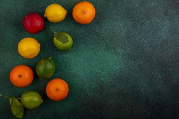 Espacio de copia de vista superior melocotón con limones limas y naranjas sobre un fondo verde